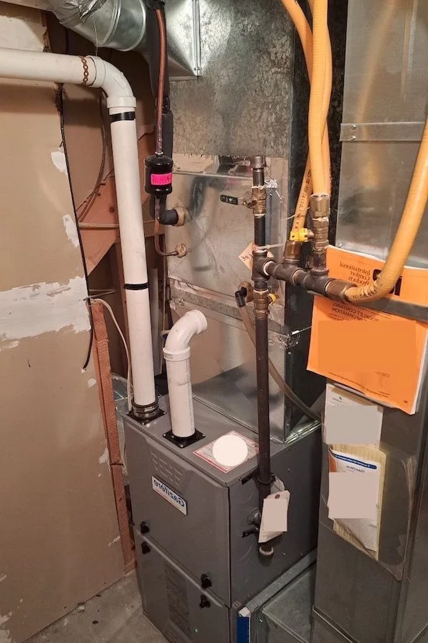 A tall, beige residential gas furnace with its front panel on, showing the manufacturer's logo.